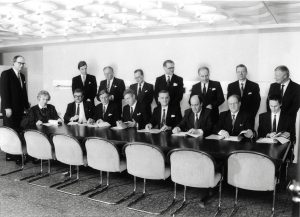 Avlångt bord med bankdirektörer som undertecknar avtal.